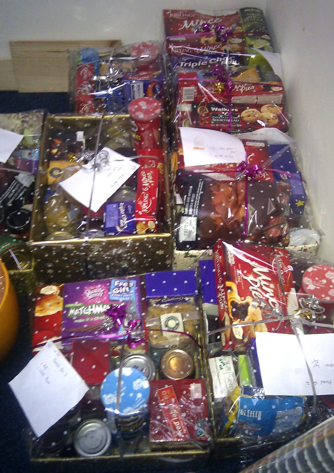 Christmas parcels wrapped in clear cellophane with ribbons, filled with mince pies, biscuits and treats